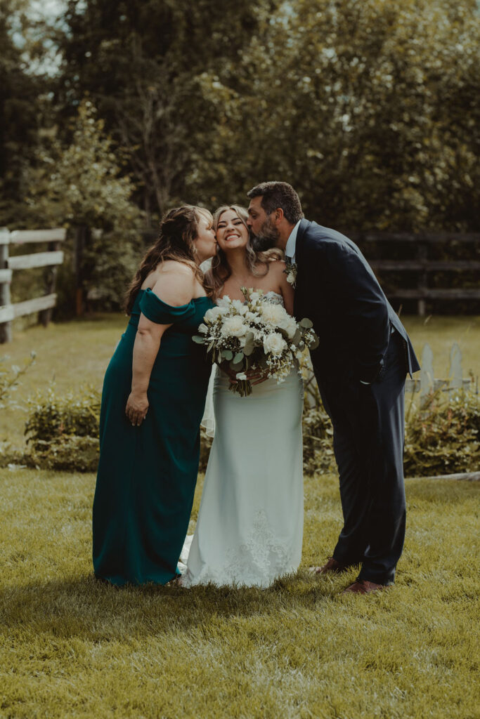 parents of the bride kissing her on the cheek