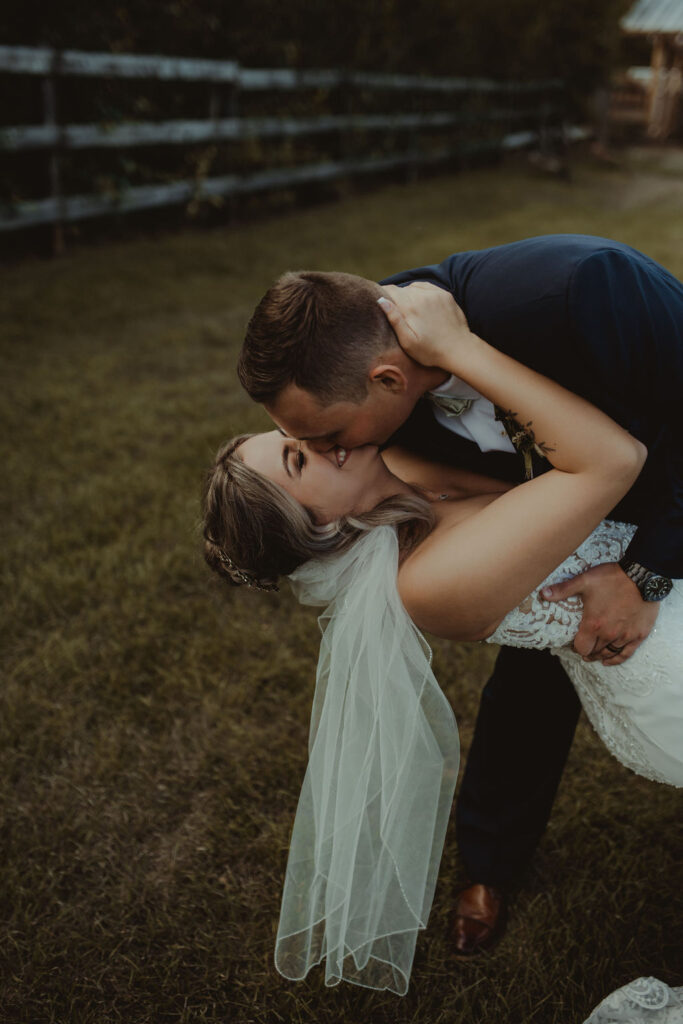 groom kissing the bride at. the rustic modern wedding