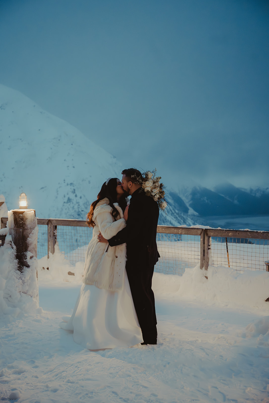 Glam bride and groom kiss at the top of Alyeska mountain on their wedding day