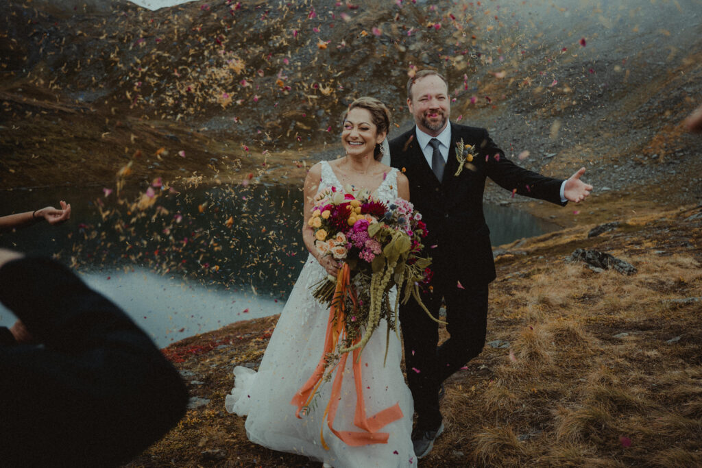 Bride and groom in a petal toss walking in Hatcher Pass