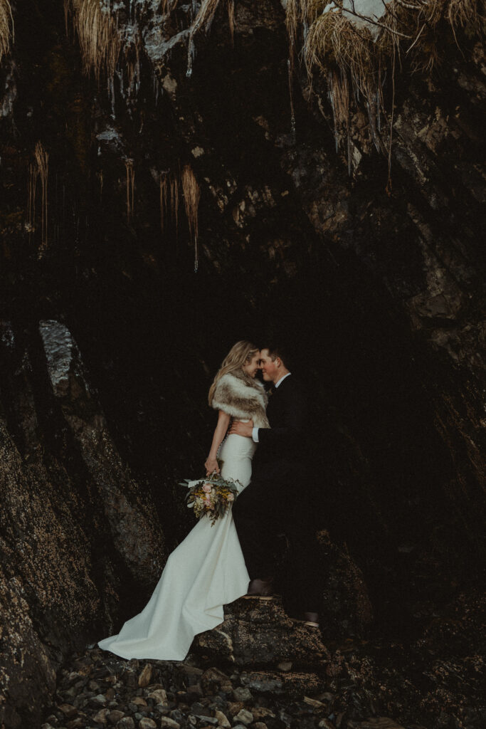 Bride and groom stand in a cave 