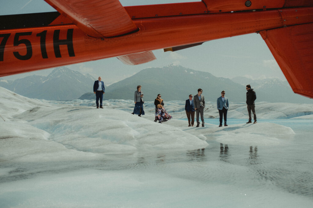 Family stand on a glacier in front of a helicopter