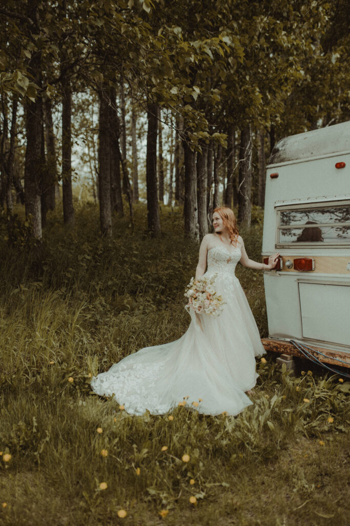 The bride poses next to the vintage bridal trailer at briarwood farm