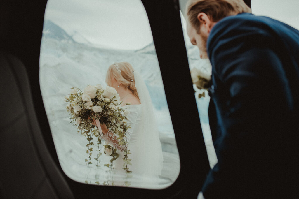 Bride and groom exit a helicopter onto a glacier