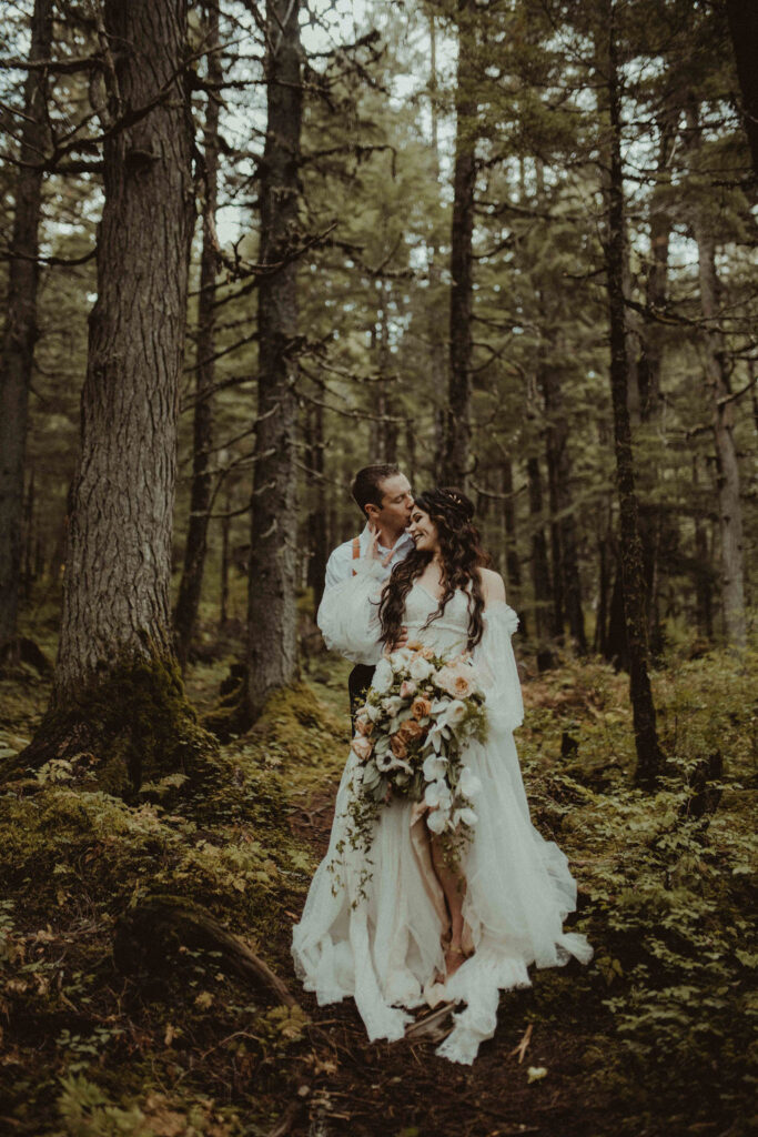 couple holding onto each other during elopement photos in the forests | Alaska Elopement: The Complete Guide