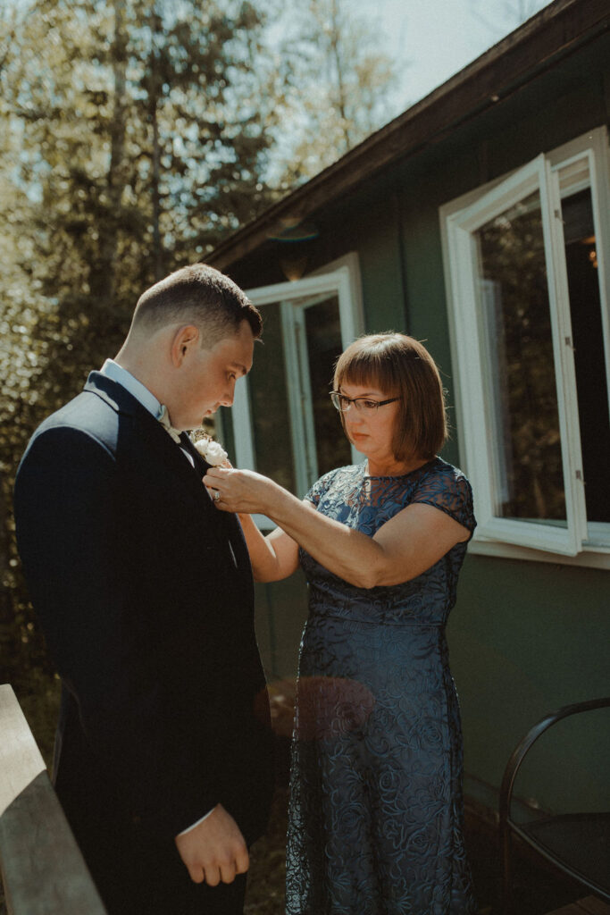 mother of the groom helping him with his tie 