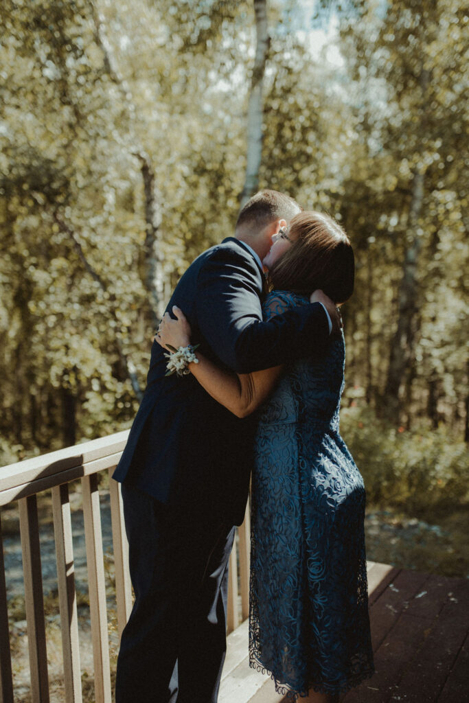 groom and his mother hugging before the rustic modern wedding ceremony