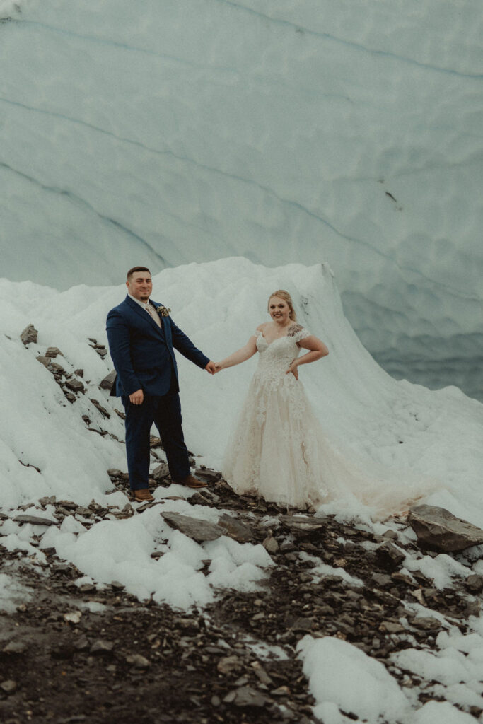 couple holding hands on top of the glacier 