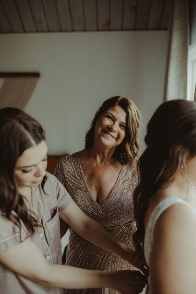 mother of the bride helping her with the wedding dress