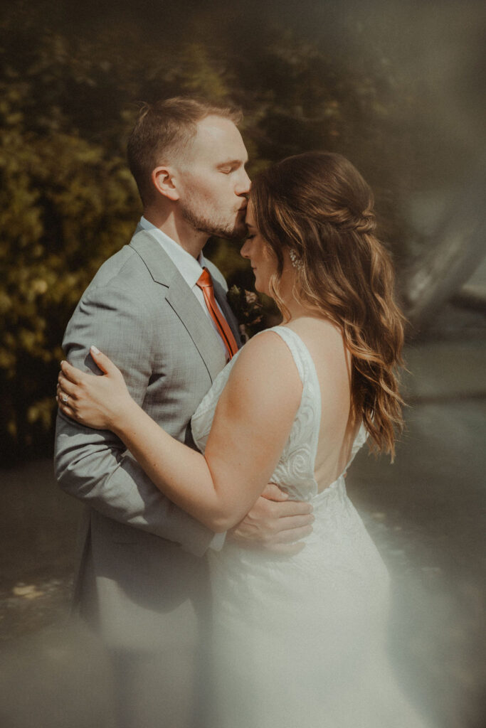 groom kissing the bride on the forehead