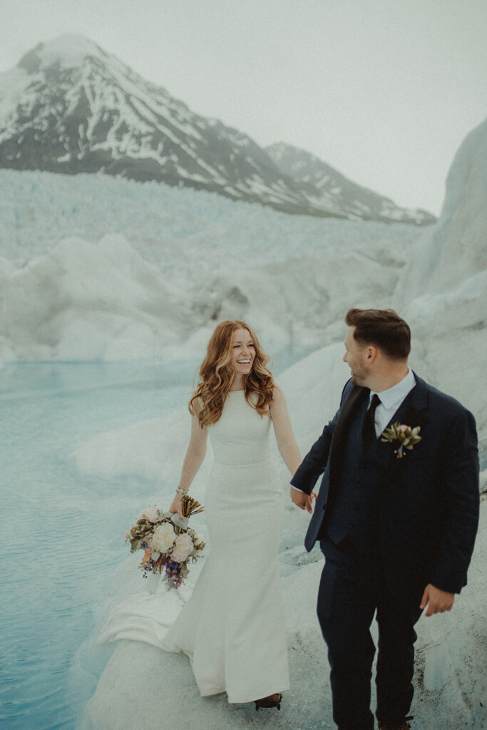 bride and groom walking around a glacier in alaska 